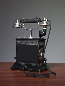 antique telephone on a desk against a grey background