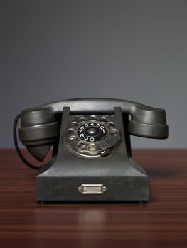 antique telephone on a desk against a grey background