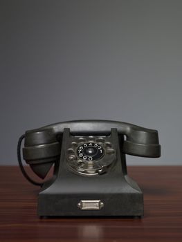 antique telephone on a desk against a grey background