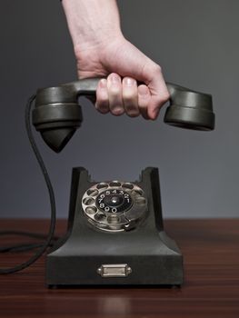 Man answering retro phone against a grey background