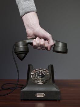 Man answering retro phone against a grey background