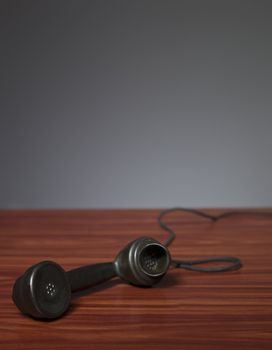 Old phone receiver on a desk with a grey background