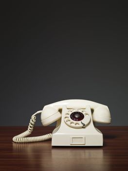 Plastic retro phone on a desk against a grey background