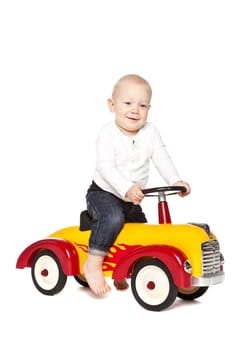 Boy riding his toycar isolated against white