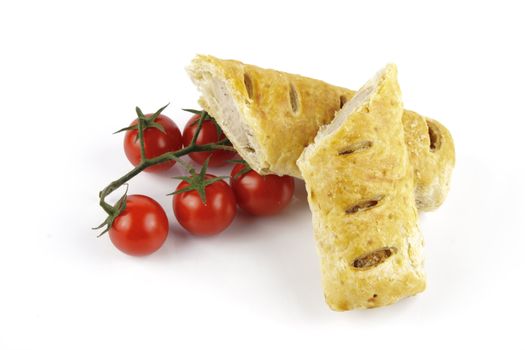 Contradiction between healthy food and junk food using tomatoes and a sausage roll on a reflective white background 