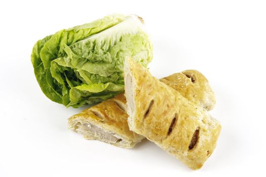 Contradiction between healthy food and junk food using a green salad lettace and sausage roll on a reflective white background 