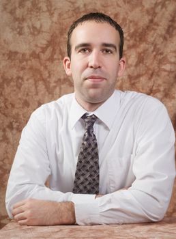 A young entrepeneur is facing the camera while wearing a white shirt and tie