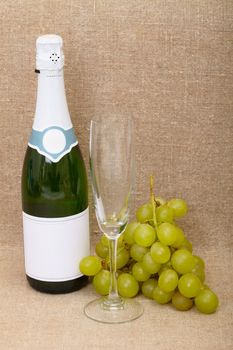 Still-life from a bottle of sparkling wine, a glass and grapes cluster
