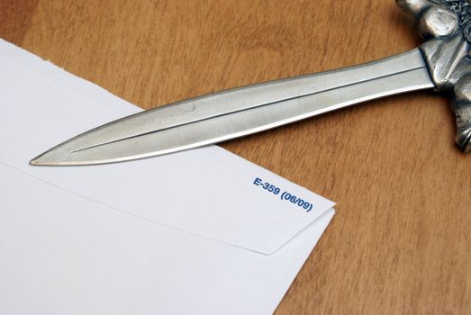 A letter opener on top of a blank envelope.