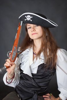 Portrait of the beautiful girl in a pirate hat with an ancient pistol in a hand