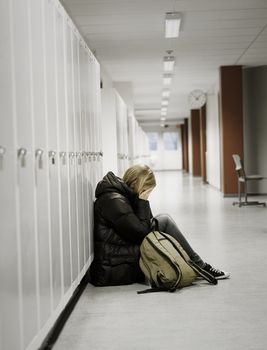 Young woman crying by the lockers at school 