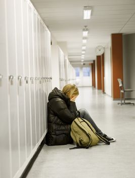 Young woman crying by the lockers at school 