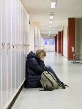 Young woman crying by the lockers at school 