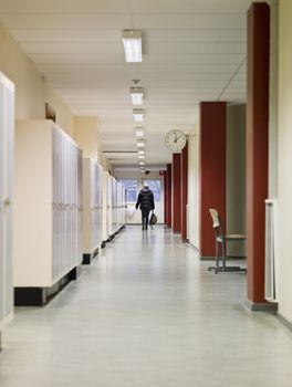 Young woman walking away through a corridor at school