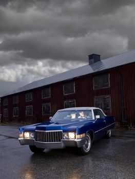 Couple sitting in and old American car on a rainy day