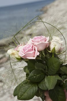 Bouquet of pink and white roses against a coastal background