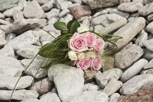 Bouquet of pink and white roses lying on rocks