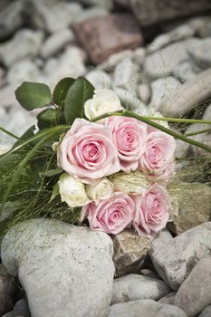 Bouquet of pink and white roses lying on rocks