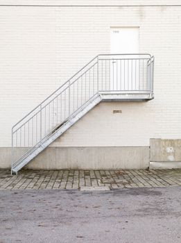 Metallic staircase against a white concrete wall