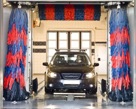 Black car with a male driver washing the car in a car wash