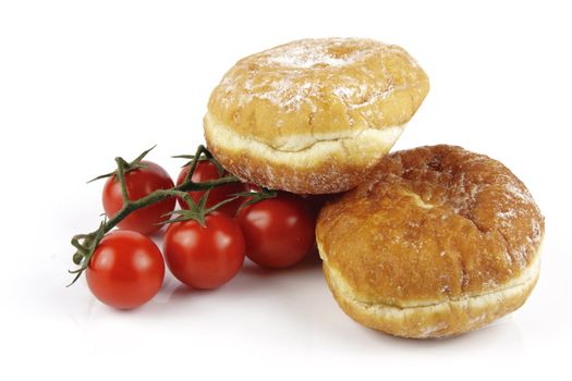 Contradiction between healthy food and junk food using red ripe tomatoes and a doughnuts on a reflective white background 