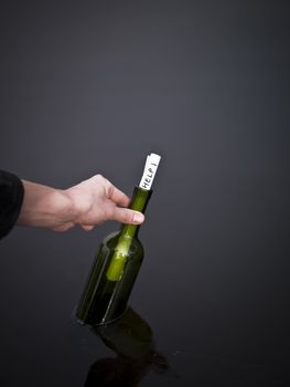 Hand picking up a bottle with a message in it.