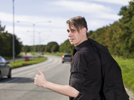 A young man hitchiking on the road