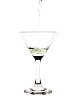 Green liquid pouring into a martini glass.