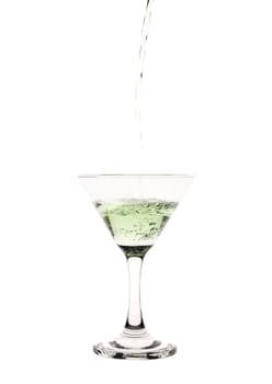 Green liquid pouring into a martini glass.