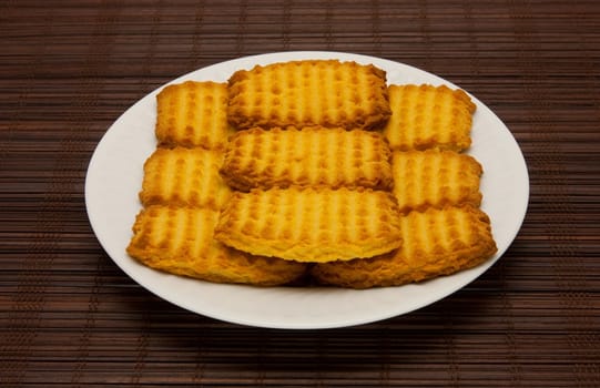 A plate of cookies on dark brown background