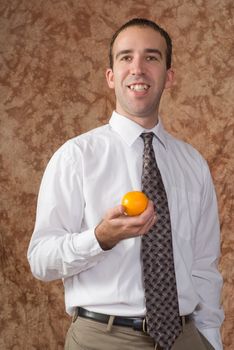 A smiling employee wearing a shirt and tie is holding an orange 