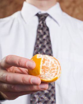 Closeup view of a businessman holding an orange that is partially peeled