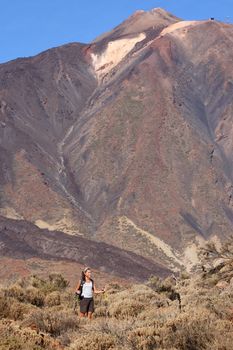 Woman hiking. Young asian female model walking with hiking poles / walking sticks during a hike / backpacking trip in the beautiful and wild volcanic landscape in the national park on the volcano, Teide, Tenerife, Spain. Lot's of copy space!