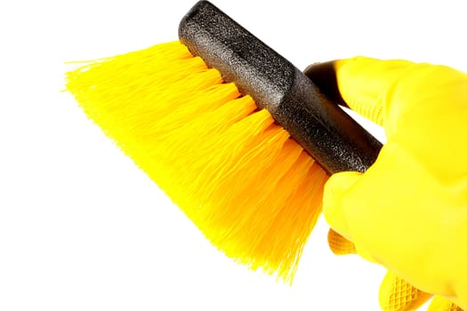 Hand in a yellow rubber glove for cleaning of premises and a brush with a yellow bristle.