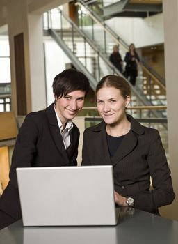 Two smiling businesswoman in front of a laptop