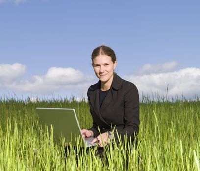Woman sitting with her laptop in the grass