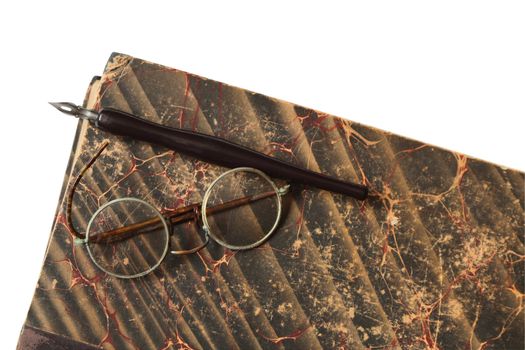 Vintage spectacles and fountain pen lying on old book. Isolated with clipping path