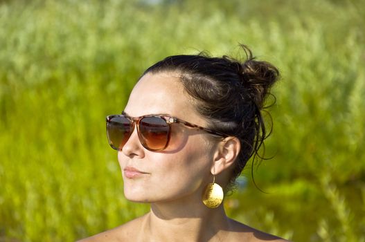 Beautiful young girl in sunglasses on the beach. Portrait. Blurred background. Summer portrait.