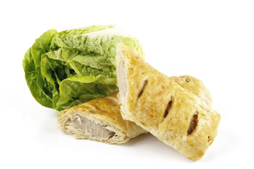 Contradiction between healthy food and junk food using a green salad lettace and sausage roll on a reflective white background 