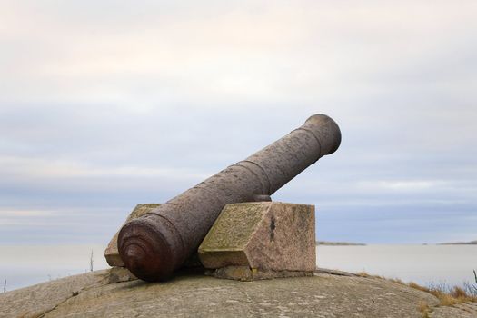 An old rusty iron cannon on Finnish coast aimed at sea.