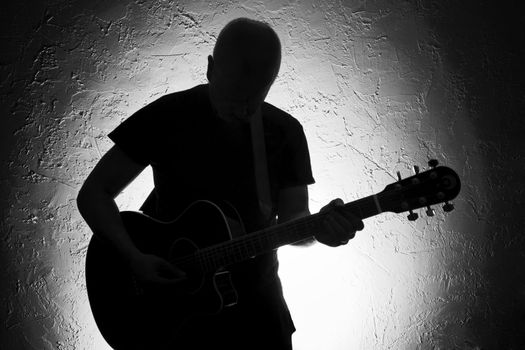 Guitar player on stage. Silhouette. Lighted background.Strong contrast. Black&white.