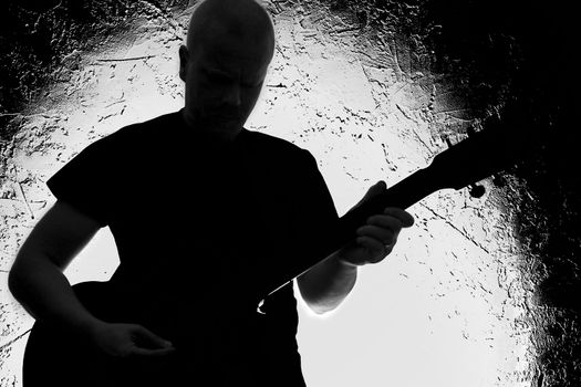 Guitar player on stage. Silhouette. Lighted background.Strong contrast. Black&white.