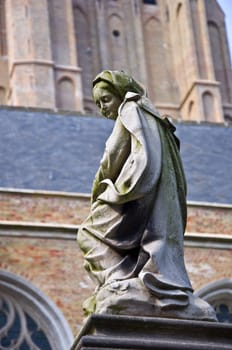 Sculpture of the Blessed Virgin Mary holy in the Catholic background of a Gothic cathedral. Shallow depth of field.