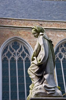 Sculpture of the Blessed Virgin Mary holy in the Catholic background of a Gothic cathedral. Shallow depth of field.