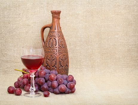 Clay jug with Georgian wine, a glass and grapes - a still-life