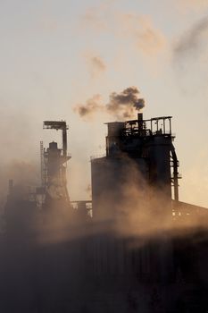 Paper mill covered by heavy smoke screen by hazy sunrise.