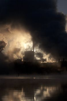 Paper mill covered by heavy smoke screen by hazy sunrise.