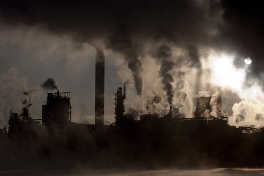 Paper mill covered by heavy smoke screen by hazy sunrise.