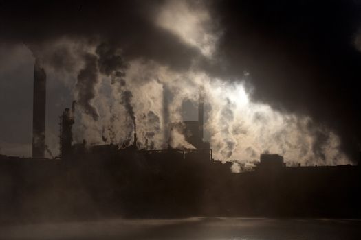 Paper mill covered by heavy smoke screen by hazy sunrise.