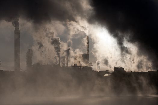 Paper mill covered by heavy smoke screen by hazy sunrise.